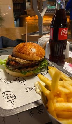 a hamburger and fries on a tray with a coke bottle in the background at a fast food restaurant