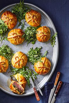 small pastries on a platter with green garnishes and knifes