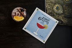 a book sitting on top of a wooden table next to a glass filled with liquid