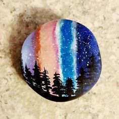 a painted rock with trees and stars on it