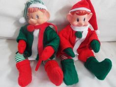 two elf dolls sitting next to each other on a bed