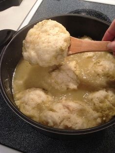 a person is stirring some food in a pot on the stove top with a wooden spoon