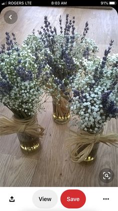 three vases filled with flowers sitting on top of a wooden floor next to a window