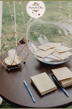 there are many pieces of paper on the table next to a glass bowl and pen