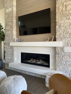 a living room with a television mounted on the wall and a fire place in front of it