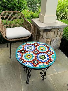 two chairs and a table on a patio with a colorful mosaic tile top sitting next to each other