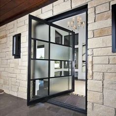 an open glass door on the outside of a brick building with a chandelier hanging from it's ceiling