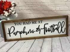 a wooden sign that says you had me at pumpkins and football on it next to a vase with flowers