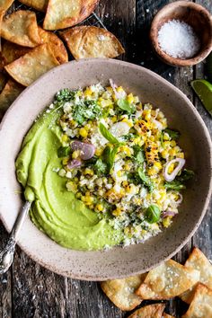 a bowl filled with guacamole surrounded by tortilla chips and salsa