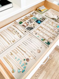 a drawer filled with lots of jewelry on top of a wooden table