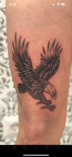 an eagle tattoo on the leg of a person's leg, with black and grey ink