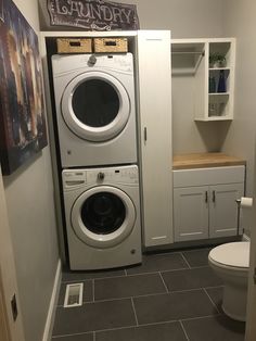 a washer and dryer in a small room with white cabinets on the wall