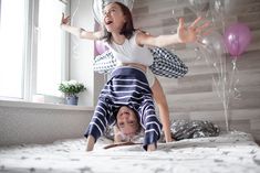 two children are playing on the bed with balloons