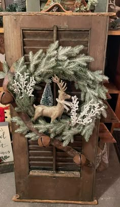 a christmas wreath on top of an old shutter with deer and snowflakes hanging from it