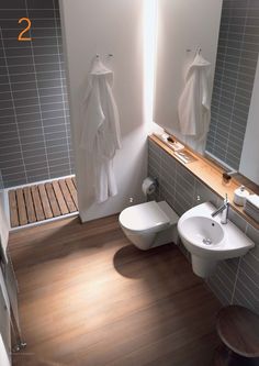 this bathroom has two toilets and a sink with the same color wood on the floor