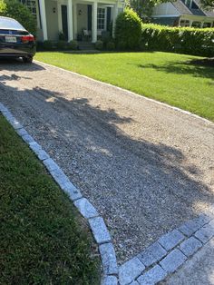 a car parked in front of a house on a gravel driveway next to a lawn