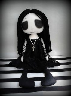 a black and white doll sitting on top of a striped floor