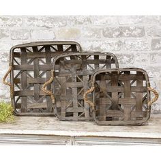 three wooden baskets sitting on top of a shelf next to a brick wall and grass