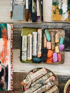 an assortment of art supplies in tins on a table