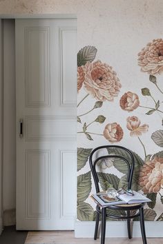 a chair sitting in front of a wall with flowers on it