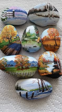 six painted rocks sitting on top of a white cloth