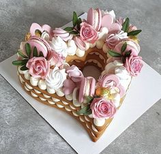 a heart shaped cake decorated with pink flowers and icing on a white paper towel