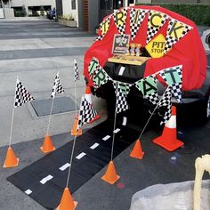 the car is decorated with race flags and signs on it's hood, along with traffic cones