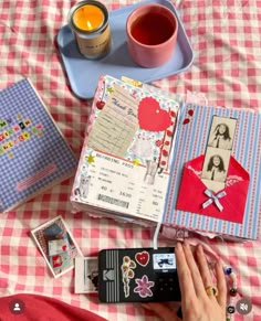 a person laying on top of a bed next to two notebooks and a cup