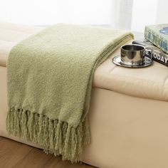 a dog bowl on a couch with a blanket over it and some books next to it