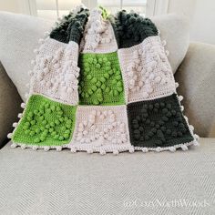 a green and white crocheted pillow sitting on top of a couch