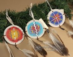 three native american dream catchers hanging from a christmas tree ornament with feathers