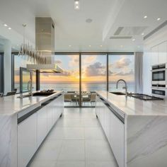 a large kitchen with an ocean view is shown in this photo, while the sun sets on the horizon