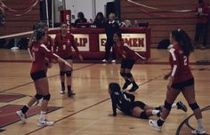 some girls are playing volleyball on a court and one girl is falling to the ground