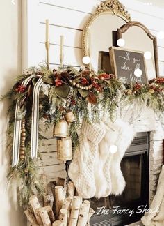 a mantel decorated with stockings, candles and christmas wreaths for the holiday season