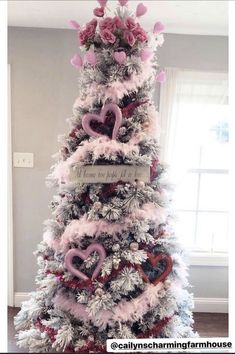 a christmas tree decorated with pink and silver ornaments, hearts and flowers on it's top