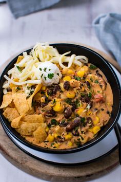 a black bowl filled with mexican food and tortilla chips