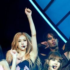 the group of girls are standing together in front of a stage with their arms up