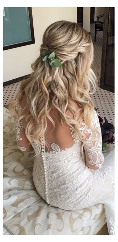 a woman sitting on top of a bed wearing a white dress and flower in her hair