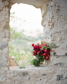 a bouquet of flowers sitting on top of a window sill next to a stone wall