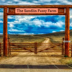 the sign for the sandin fuzzy farm is in front of a dirt road and fence