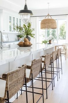 a kitchen with white counter tops and wicker chairs