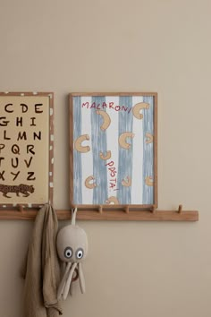 an elephant stuffed animal hanging on a wall next to a wooden sign with letters and numbers