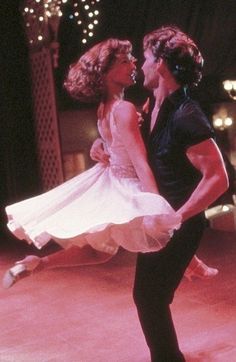 a man and woman dancing on stage in the middle of a dance floor with lights behind them