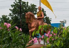 a man riding on the back of a brown horse next to a flag and flowers