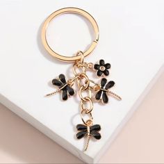 a black and gold keychain with flowers on it sitting on top of a white surface