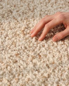 a person's hand resting on the carpet