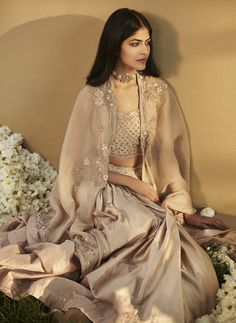 Editor's Note Presenting a Tuscan Gold Roman Cape Set, featuring breathtaking floral embroidery with extensive and intricate handwork. The cape, crafted from fine luxurious organza, showcases delicate floral embroidery of Resham and Nakashi Zardozi. The blouse boasts a scooped neckline and no sleeves, adorned with small sequined booties all across. The skirt, based on Chanderi silk, features gathers on the waist and is attached to a heavy embellished belt with mirror work. Fabric: Chanderi silk Cape Set, Personal Shopping Service, Embellished Belt, Scooped Neckline, Mirror Work, Last Minute Gifts, Every Girl, Modern Classic, Floral Embroidery