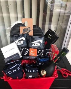 a red basket filled with lots of items on top of a table next to a window