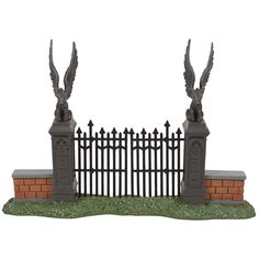 an iron fence with two birds on it and a brick wall in the foreground