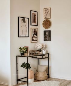 a table with some pictures on the wall above it and a potted plant next to it